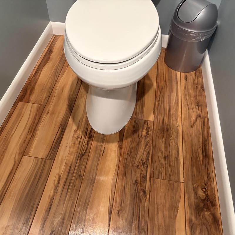 Toilet installation on wood laminate flooring and trash can