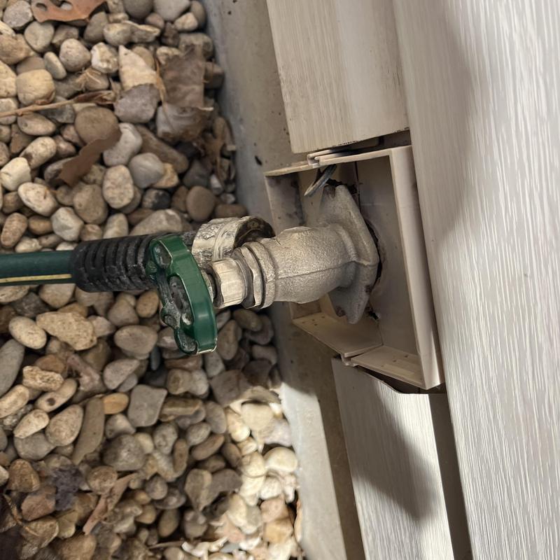 Hose bib connection with green handle on exterior wall