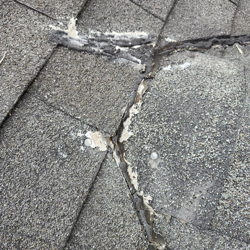 Asphalt roof shingles with visible aging and sealant degradation
