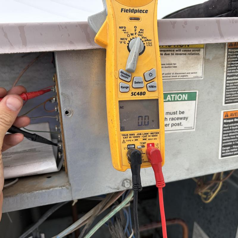 Rooftop HVAC unit electrical testing with multimeter