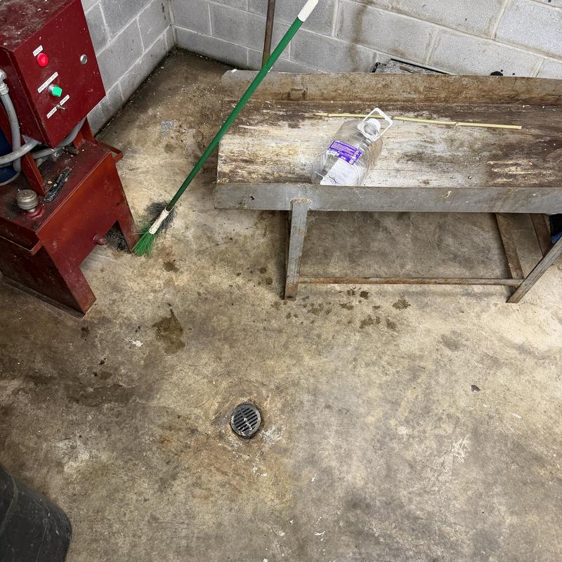 Floor drain in basement with broom and bench Floor drain in basement with broom and bench