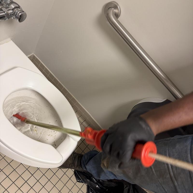 Toilet drain auger clearing clog in restroom toilet Toilet drain auger clearing clog in restroom toilet