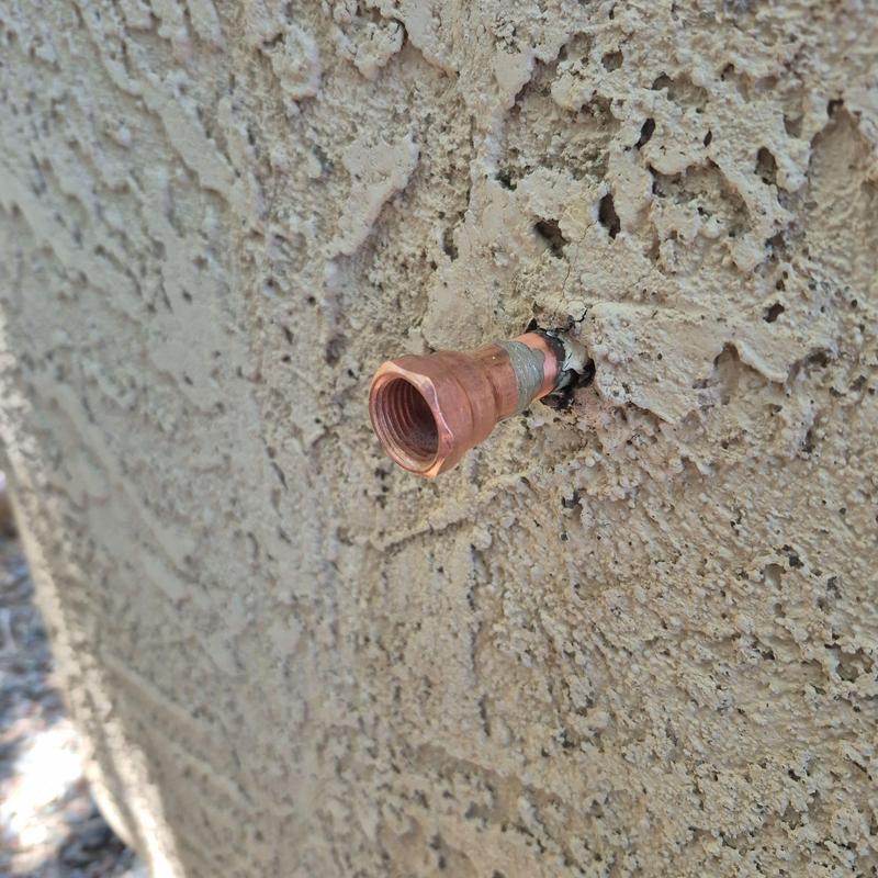 Outdoor hose bib copper fitting on stucco wall