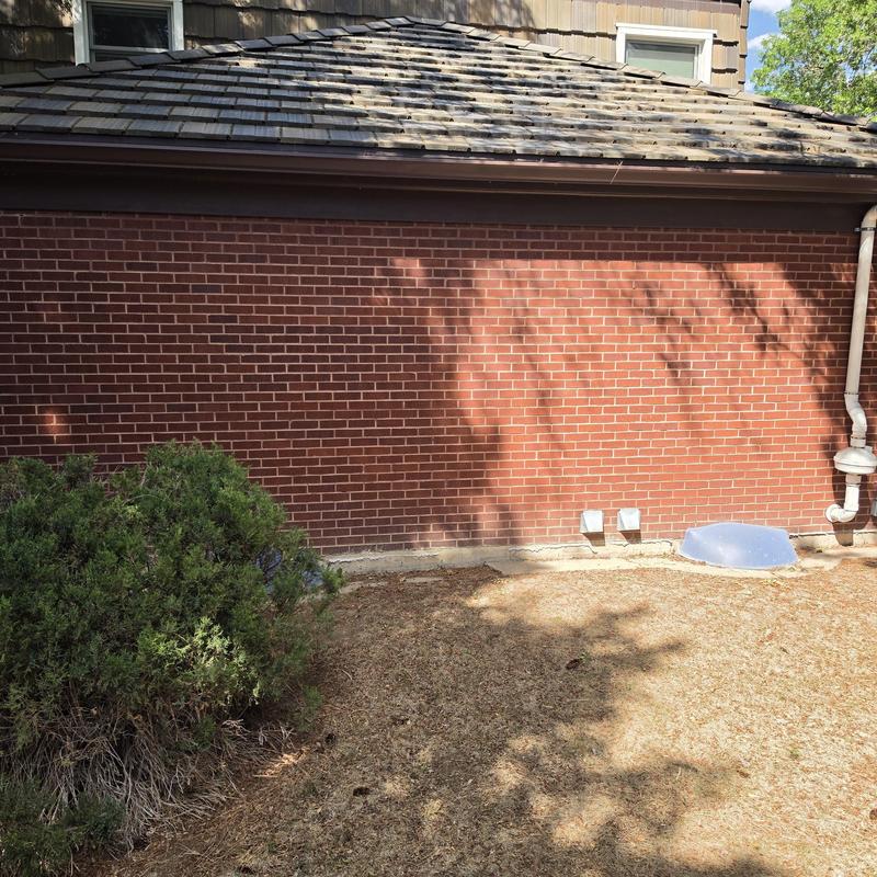 Brick wall exterior with ground vent and drainage pipe