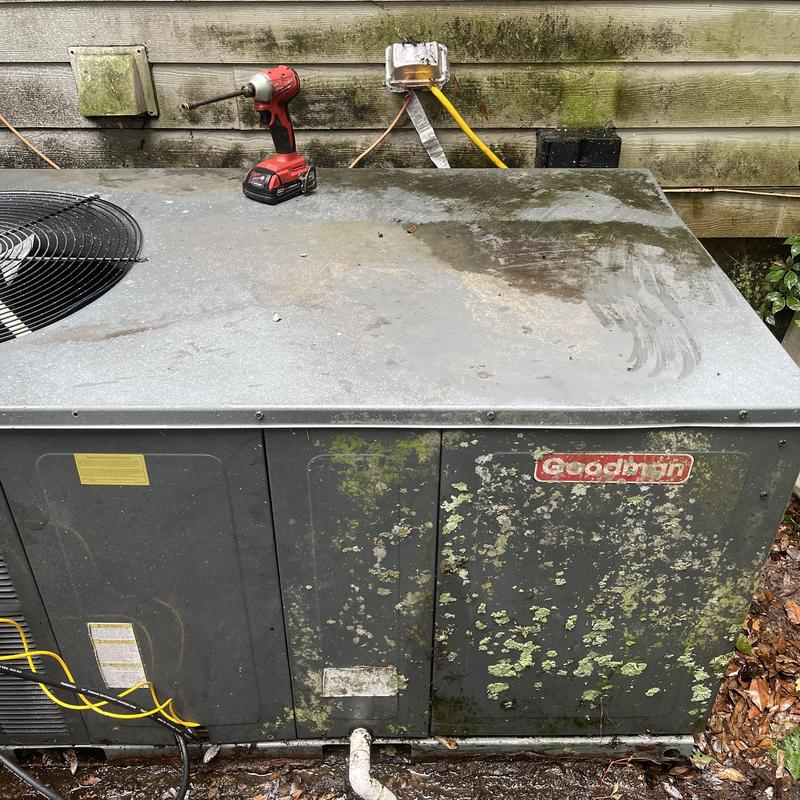 Condenser coil on outdoor HVAC unit with drill on top
