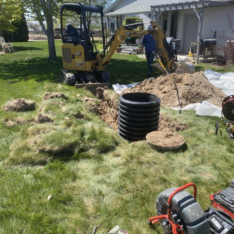 Septic tank riser installation with excavator in yard