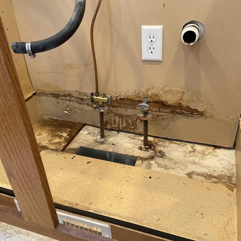 Kitchen sink plumbing with angle stops exposed and damaged wall