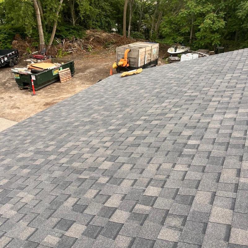 Asphalt shingle roof with cleanup equipment in background
