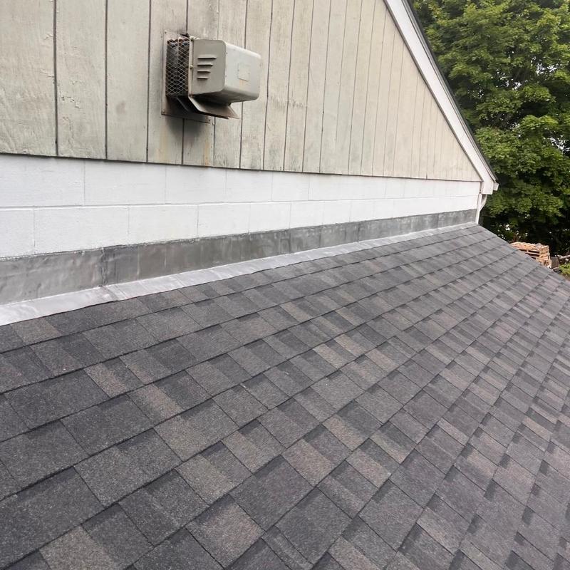 Asphalt shingle roof with metal flashing near vent