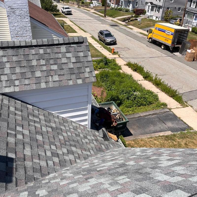 Asphalt shingle roof with clean-up container in driveway