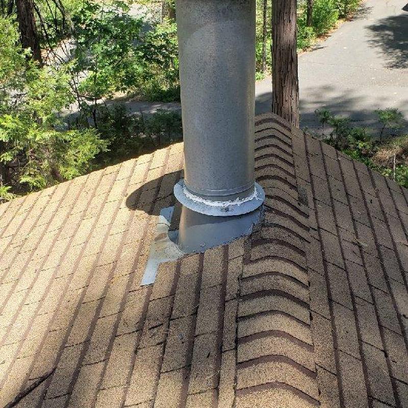 Asphalt shingle roof around metal chimney flashing