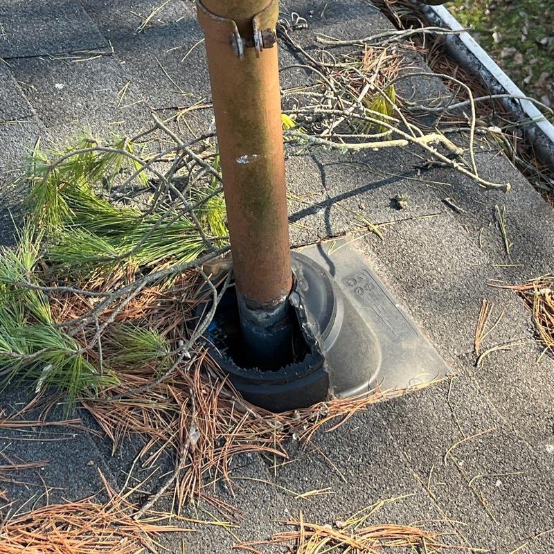 Roof vent pipe flashing with damage and debris on roof
