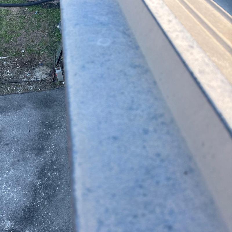 Metal roof edge with hail damage on commercial building