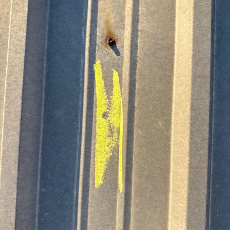Metal commercial roof panel with hail damage mark