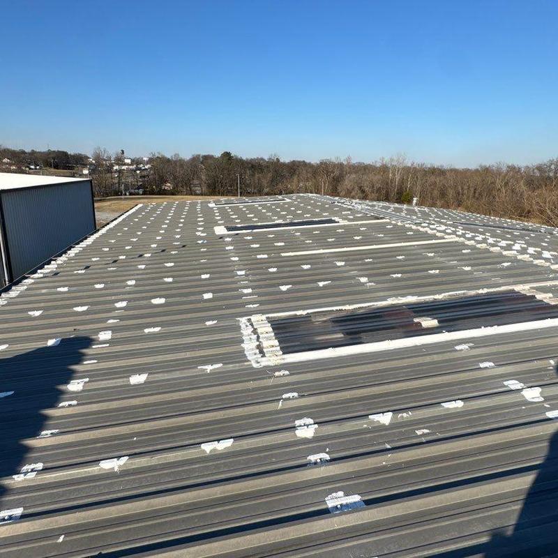 Metal commercial roof with hail damage repairs visible