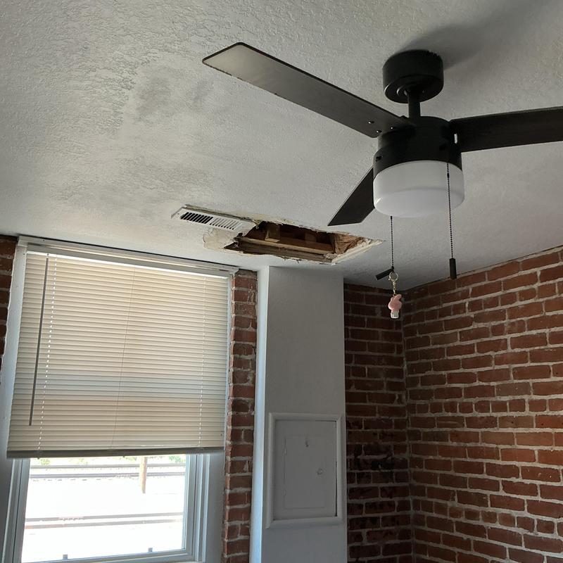 Ceiling water damage and hole from leak above tub shoe