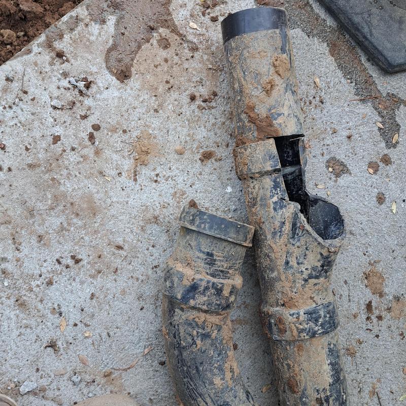 Broken sewer line pipe with dirt debris on concrete Broken sewer line pipe with dirt debris on concrete