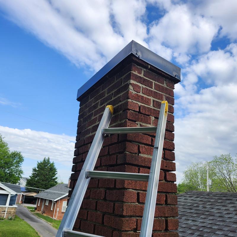 Chimney with handmade metal cap and ladder on roof