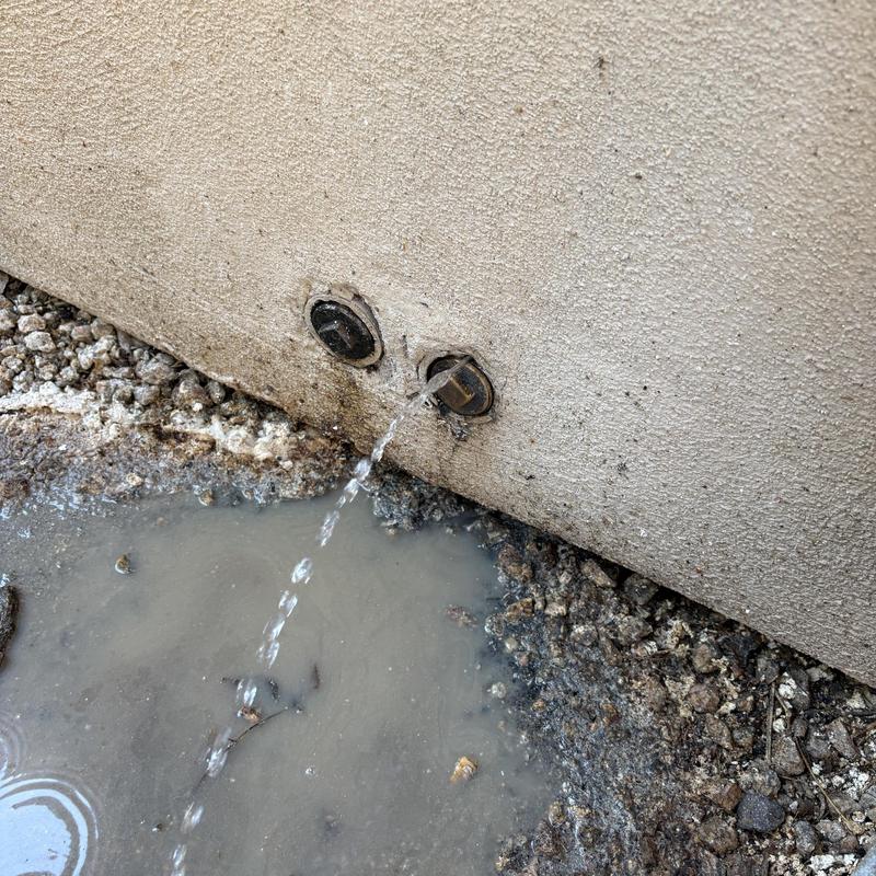 Leaking exterior water line with water spraying from wall connection
