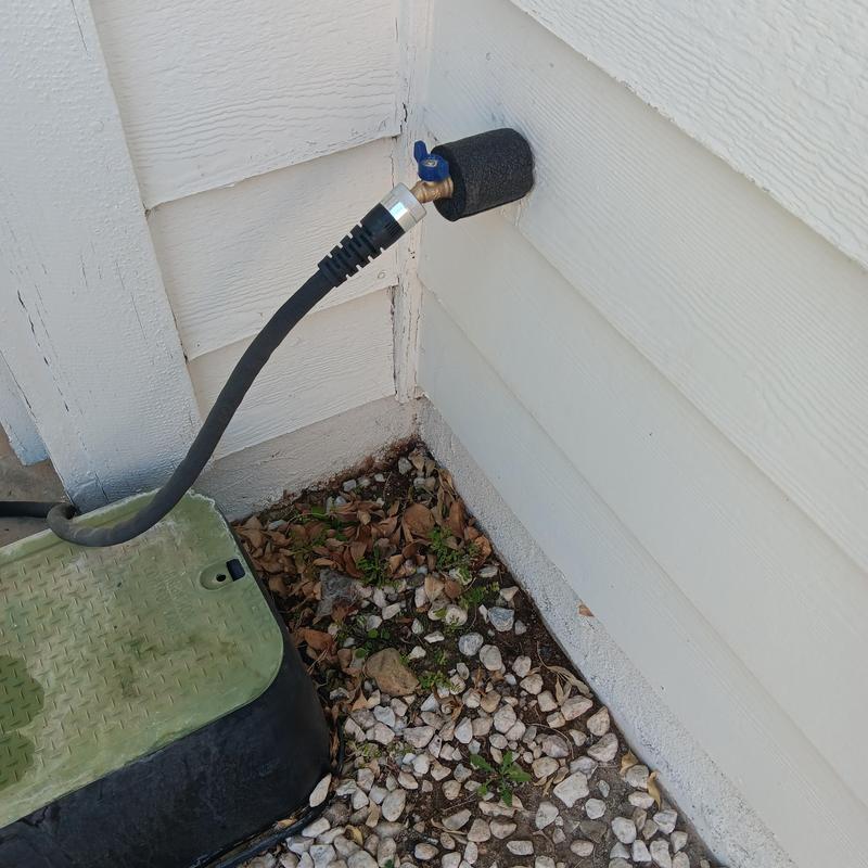 Hose bib with attached garden hose outside house