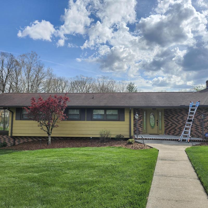 Asphalt shingle roof with missing ridge cap and ladder