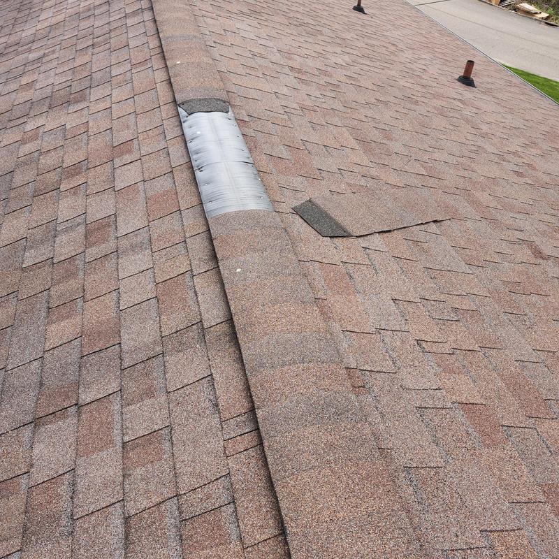 Ridge cap with missing shingles on aged roof