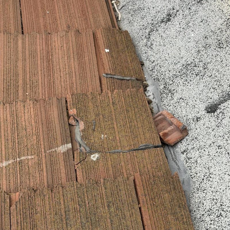 Broken flat roof tiles with visible cracks and damage Broken flat roof tiles with visible cracks and damage