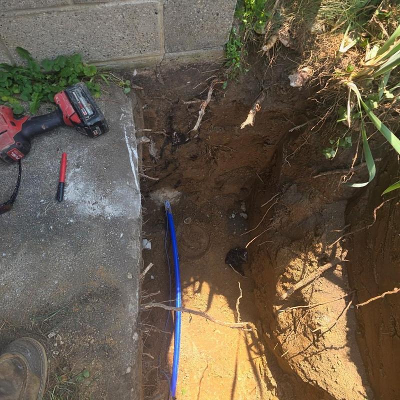 Blue water service line installation in trench near sidewalk