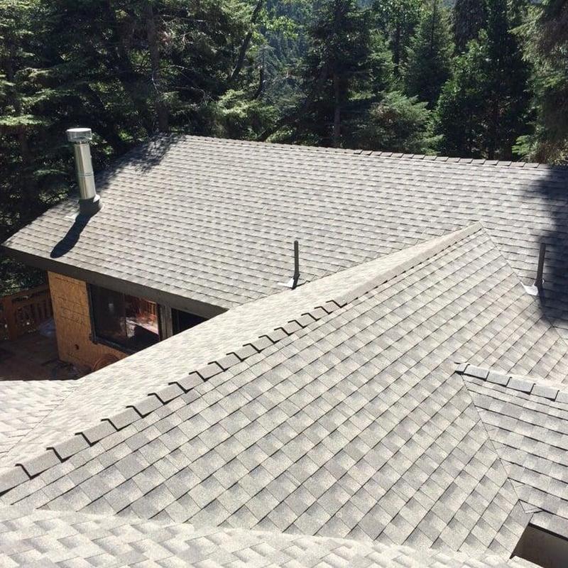 Shingle roof installation with ridge vents in forested area Shingle roof installation with ridge vents in forested area