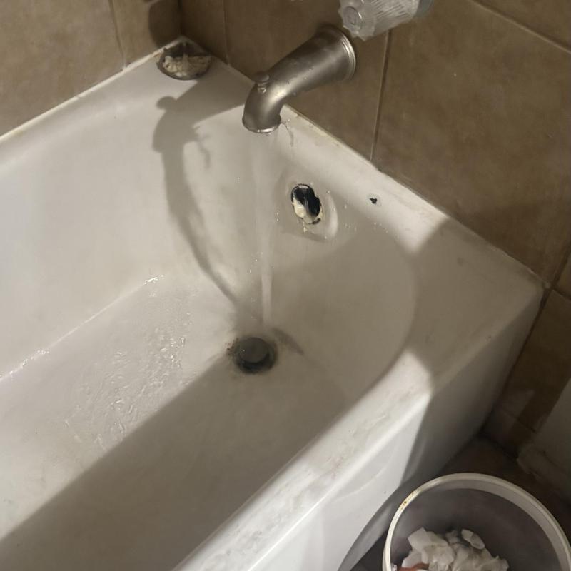 Bathtub faucet with running water and drain visible