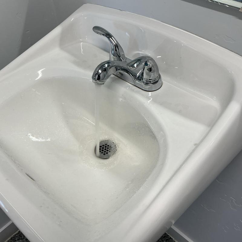 Bathroom faucet with water running into sink basin Bathroom faucet with water running into sink basin