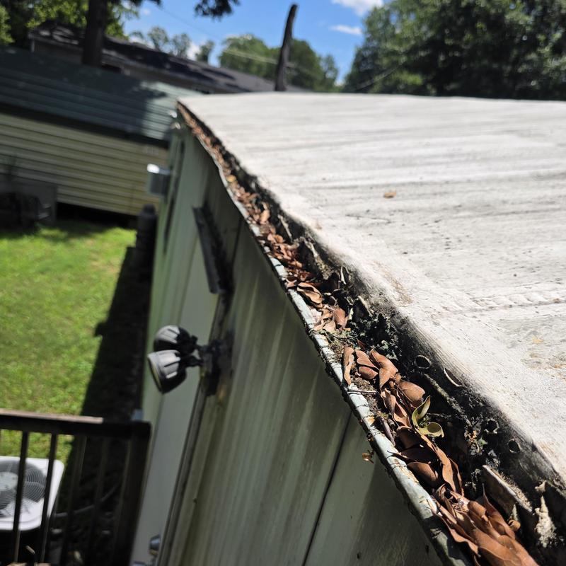 Mobile home gutter clogged with leaves and debris
