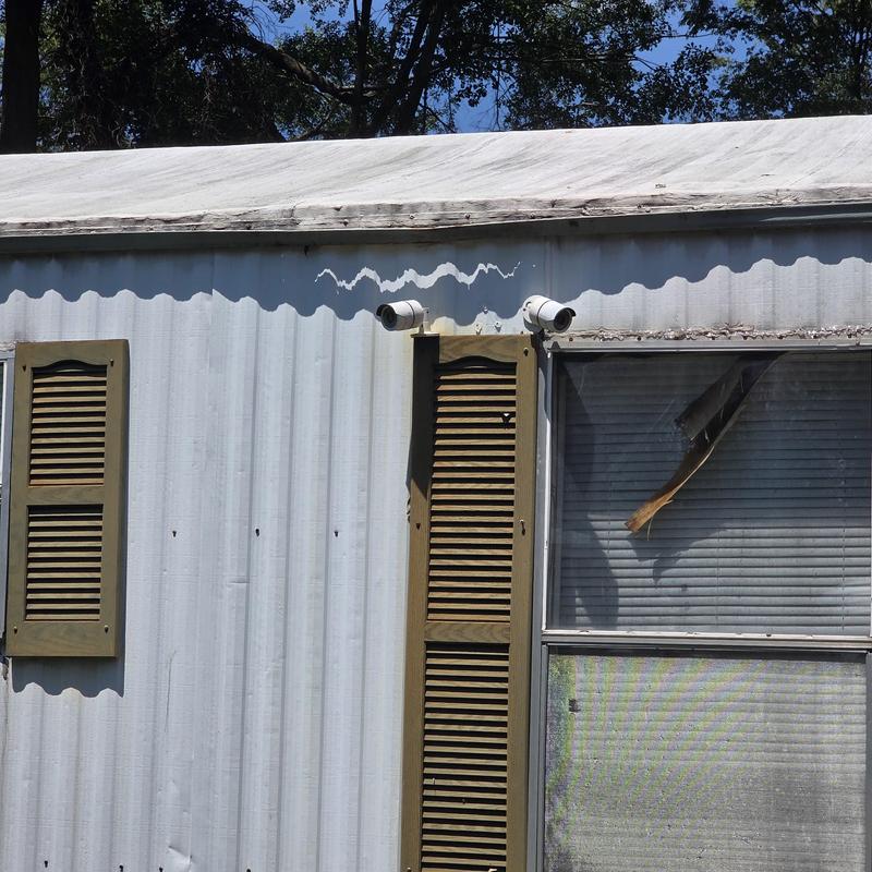 Mobile home window with damaged blinds and shutters