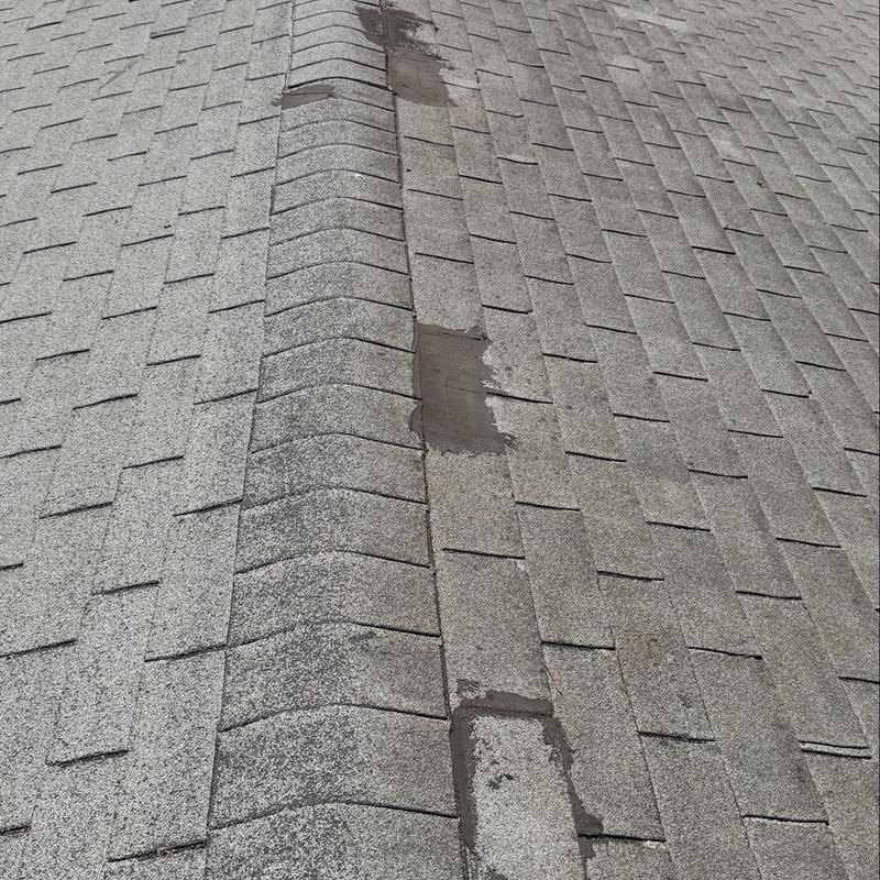 Shingle roof ridge with patch repairs and wear Shingle roof ridge with patch repairs and wear