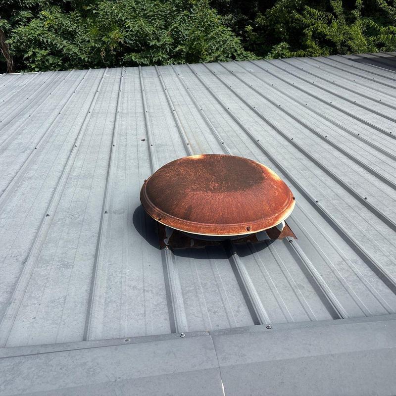 Rusty roof vent on metal roofing panel Rusty roof vent on metal roofing panel