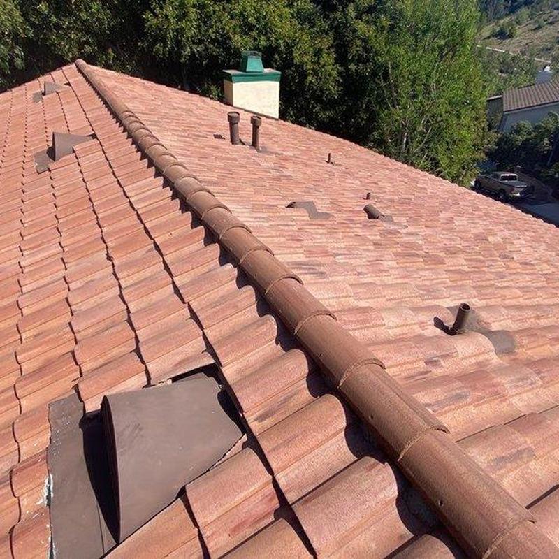 Tile roof with ridge cap and vent pipes in sunlight Tile roof with ridge cap and vent pipes in sunlight