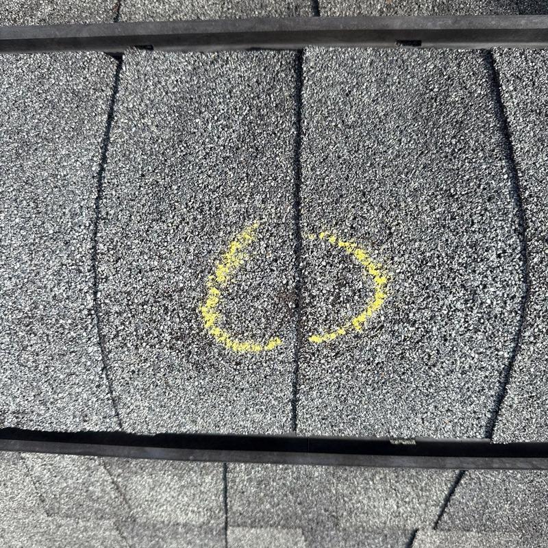 Asphalt roof shingle hail damage marked for repair