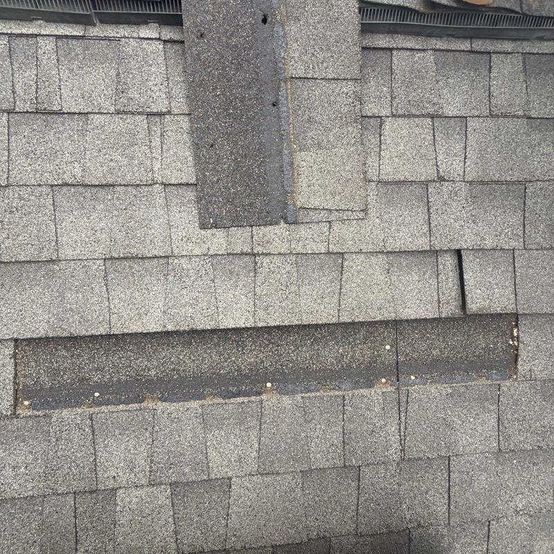 Roof shingles with missing and damaged sections on roof slope