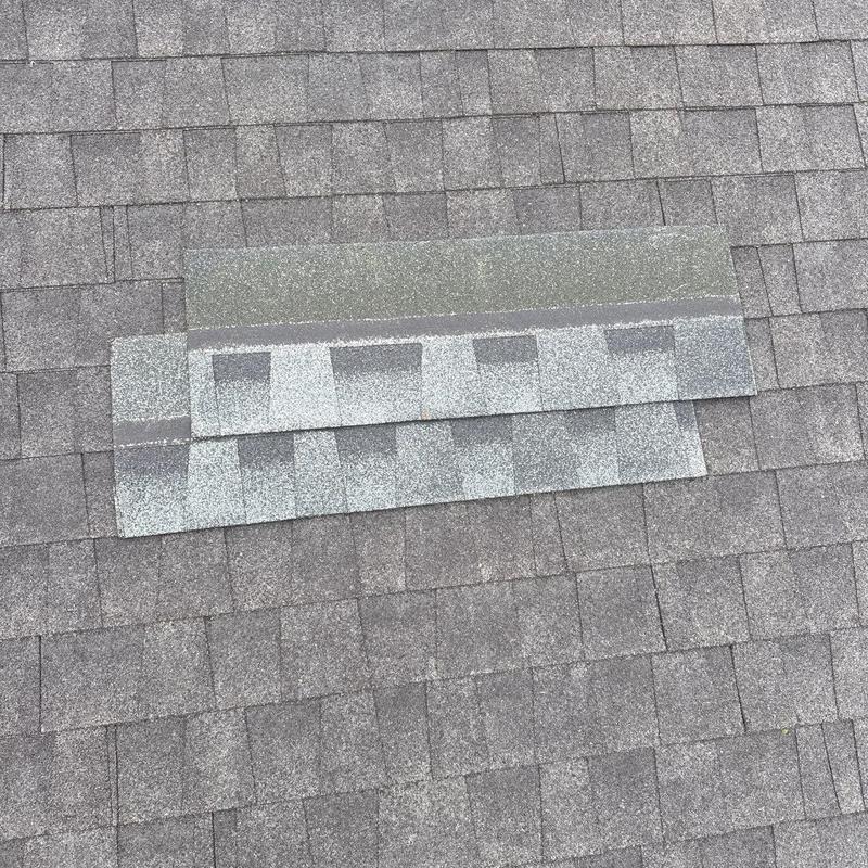 Asphalt roof shingles with hail damage on repair test area