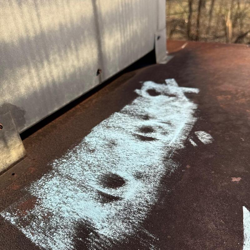 Rusty metal roof panel with hail damage chalk marks