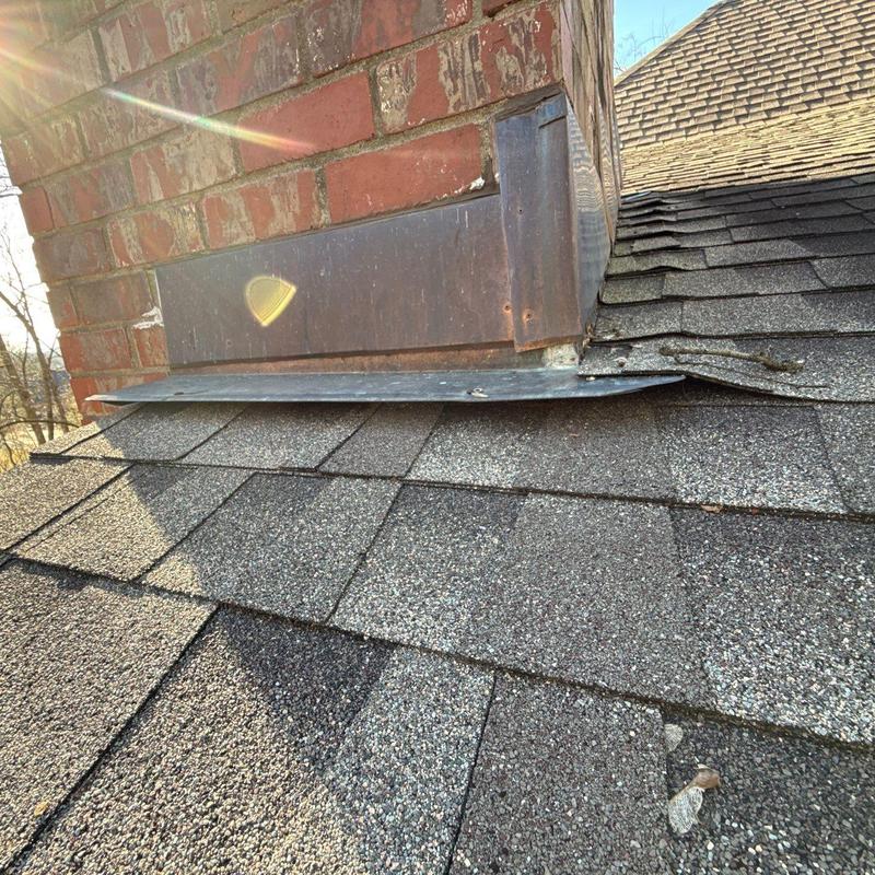 Metal chimney flashing on shingle roof with hail damage