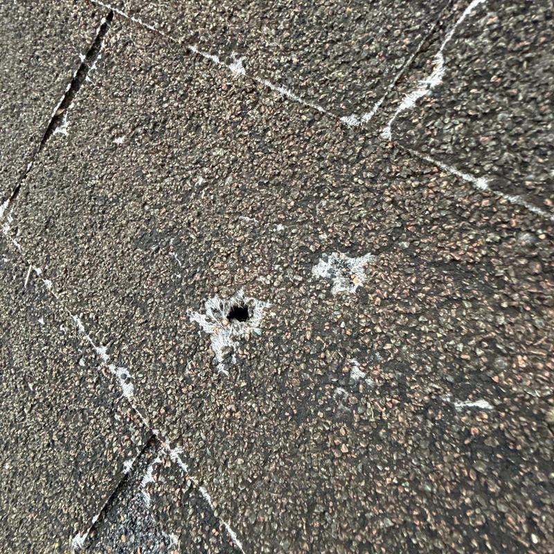 Asphalt shingle roof with hail damage hole marked