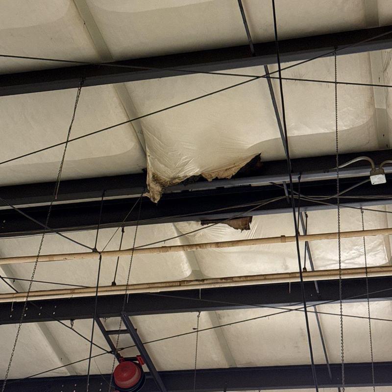 Spray foam insulation with tear damage on ceiling beams