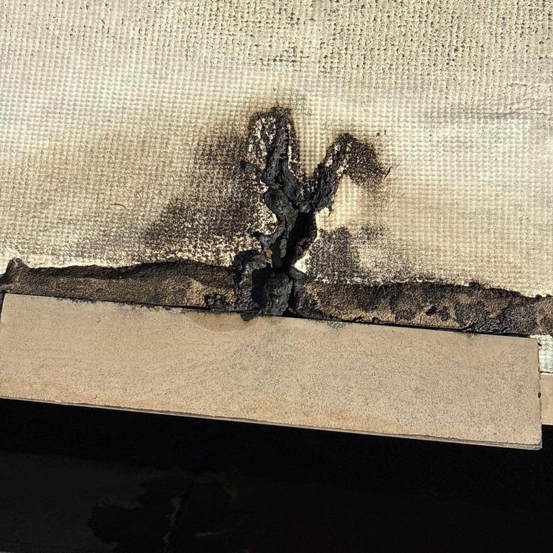 Roof membrane with burn damage and cracks near flashing