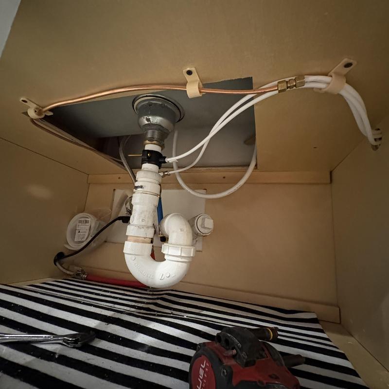 Reverse osmosis system plumbing lines inside kitchen cabinet
