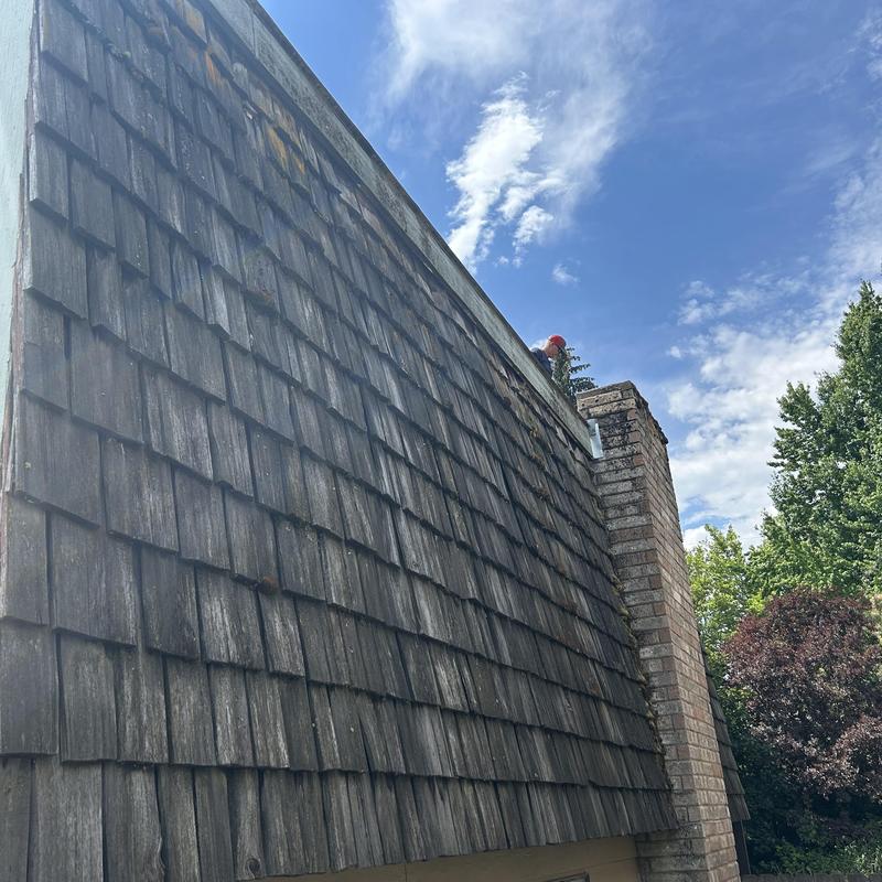 Wood shingle roof inspection near brick chimney Wood shingle roof inspection near brick chimney