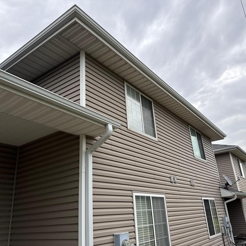 Aluminum gutters and downspouts on beige siding house Aluminum gutters and downspouts on beige siding house