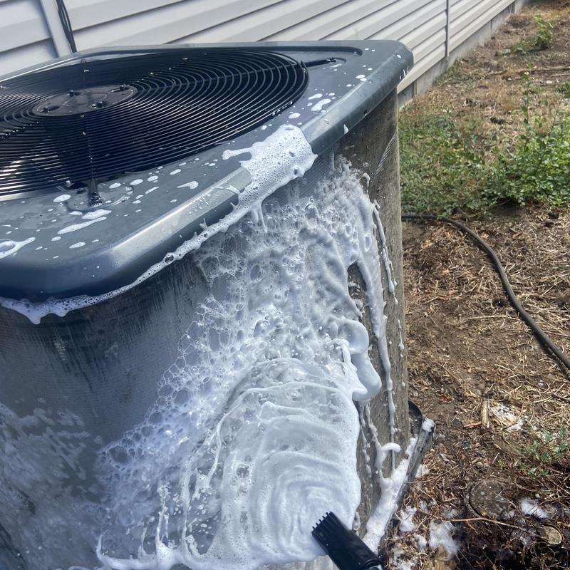Outdoor air conditioner condenser being cleaned with foam brush Outdoor air conditioner condenser being cleaned with foam brush