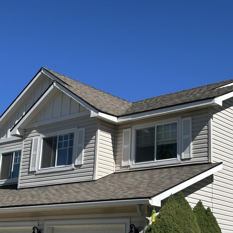 Asphalt shingle roof on two-story house under clear sky Asphalt shingle roof on two-story house under clear sky
