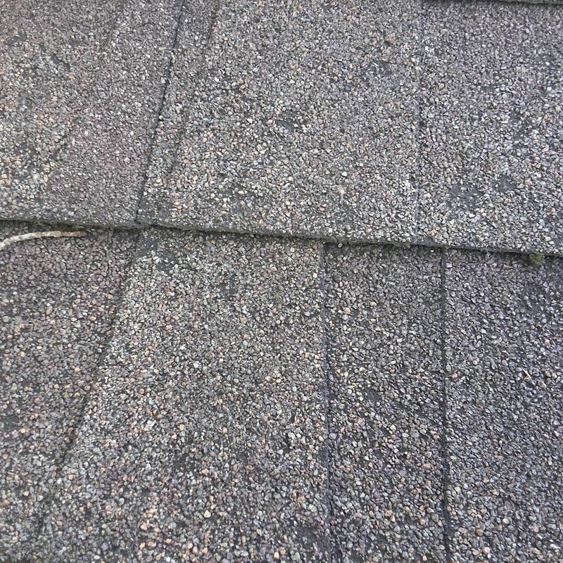 Asphalt shingle roof close-up with visible lift and wear